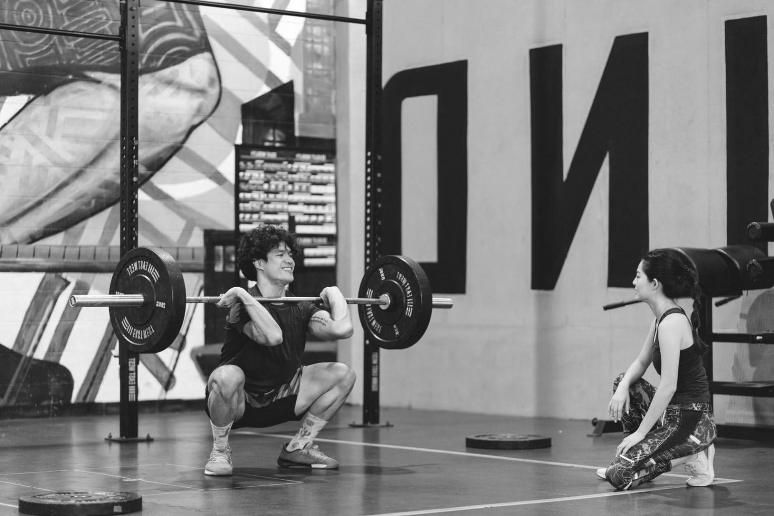 Юна гімнастка виконує елемент на колоді під наглядом тренера